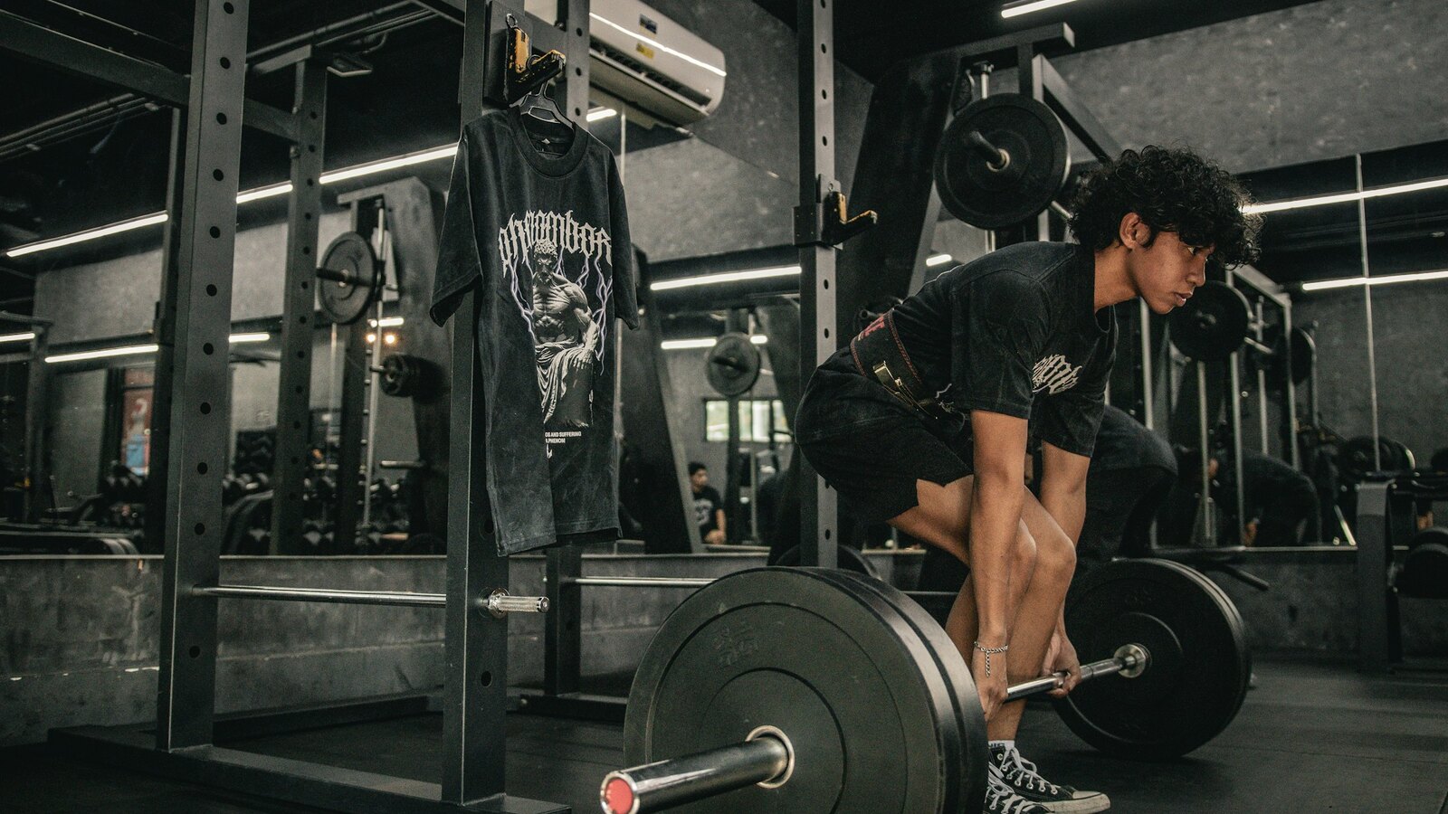Lifter pulling a heavy loaded barbell in a dark chalked gym